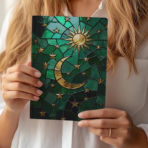 Peut inclure: Un carnet avec un motif de vitrail représentant un soleil doré, un croissant de lune et des étoiles sur fond vert. La couverture présente un motif de mosaïque avec des accents dorés. Le carnet est tenu par une personne portant une chemise blanche.
