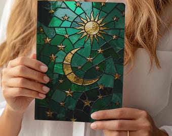May include: A notebook with a stained glass design featuring a gold sun, crescent moon, and stars on a green background. The cover has a mosaic pattern with gold accents. The notebook is held by a person wearing a white shirt.