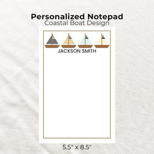 Könnte beinhalten: Ein personalisierter Notizblock mit einem Küstenboot-Design. Der Notizblock zeigt vier Segelboote mit unterschiedlich farbigen Segeln über dem Namen "JACKSON SMITH". Der Notizblock misst 14 cm x 22 cm.