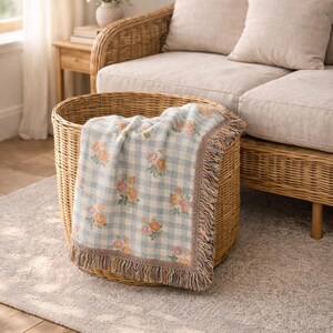 Vintage inspired botanical blanket folded in a woven basket in cottage living room