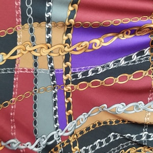 May include: A fabric with a chain link pattern in gold, silver, and brown on a red, purple, black, and gray background.
