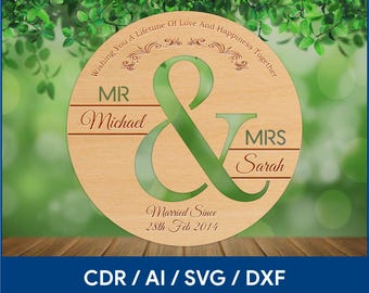 May include: A wooden round sign with the text "Wishing You A Lifetime Of Love And Happiness Together" and "Married Since 28th Feb 2014". The sign features a large ampersand with the words "MR Michael" and "MRS Sarah" on either side. The sign is on a wooden surface with a green background.