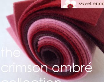May include: A roll of felt fabric in various shades of red and pink, from deep crimson to light blush. The felt is rolled up and tied with a white ribbon. The text "sweet emma jean" is visible on the top of the roll. The text "the crimson ombré collection" is visible below the roll.