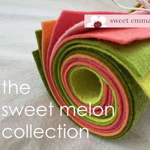 May include: A roll of felt fabric in shades of green, orange, and pink. The felt is rolled up and tied with a white ribbon. The text "sweet emma jean" is printed on the top of the roll. The text "the sweet melon collection" is printed below the roll.