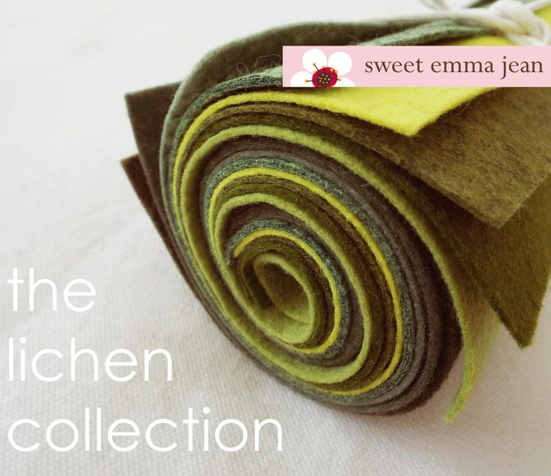 Puede incluir: Un rollo de tela de fieltro en tonos verdes y amarillos. El fieltro est&aacute; enrollado apretadamente y los extremos son visibles. El texto "the lichen collection" est&aacute; impreso debajo del rollo de fieltro. El texto "sweet emma jean" est&aacute; impreso en una etiqueta blanca con una flor rosa y una mariquita roja.