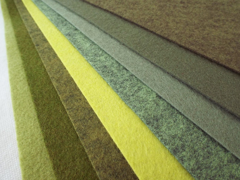 Puede incluir: Una colecci&oacute;n de muestras de tela de fieltro en varios tonos de verde y amarillo. Las muestras est&aacute;n dispuestas en forma de abanico, con el verde m&aacute;s oscuro en la parte superior y el amarillo m&aacute;s claro en la parte inferior.