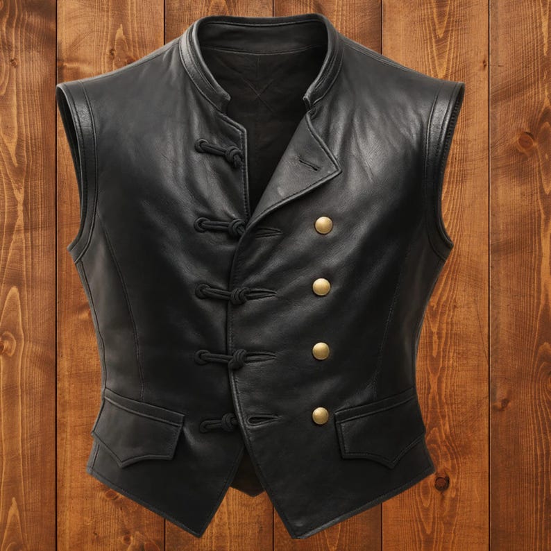 May include: A black leather vest with a mandarin collar and a double-breasted design. The vest features four gold-colored buttons and decorative knot closures. Two small pockets are visible at the waist.