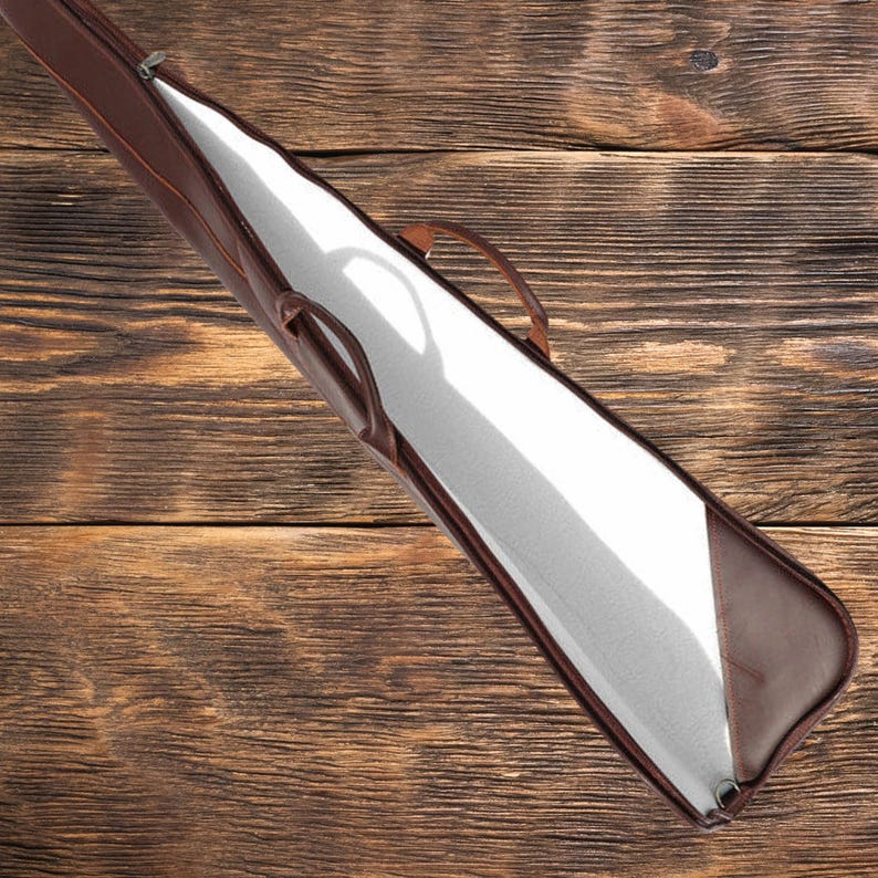 May include: A brown leather gun case with a white lining and a zipper closure. The case is open and the lining is visible.