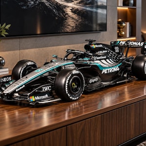 Puede incluir: Un modelo a escala detallado de un coche de carreras de Fórmula 1 Mercedes-AMG Petronas negro y plateado, con el número 12, la marca de neumáticos Pirelli y varios logotipos de patrocinadores como IWC, Microsoft, Ineos y TeamViewer en su carrocería.