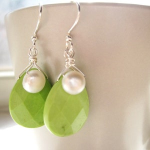 May include: A pair of silver earrings with green gemstone drops and white pearl accents.