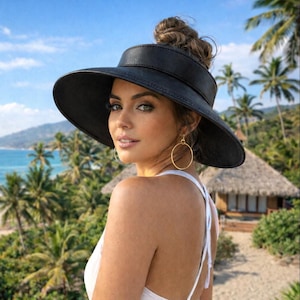 May include: A black visor hat with a wide brim. The hat is worn by a person with a white top and gold hoop earrings. The background features a tropical beach scene with palm trees, a blue ocean, and a small building.