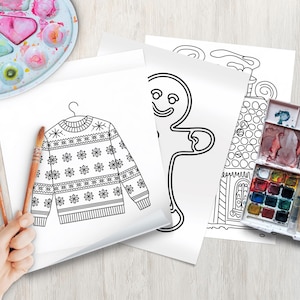 Könnte beinhalten: Eine Sammlung von Malvorlagen zum Thema Weihnachten mit einem Pullover, einem Lebkuchenmann und einem Haus. Aquarellfarben und Pinsel sind auf einer hellen Holzoberfläche angeordnet, was auf eine kreative Aktivität hindeutet. Die Seiten sind Schwarz-Weiß-Strichzeichnungen.