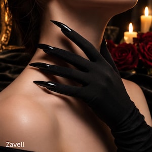May include: Black opera-length gloves featuring integrated long, pointed, glossy black claw-like fingernail extensions on each finger. The fabric is a solid matte black material. The word Zavell is printed in white in the bottom corner.