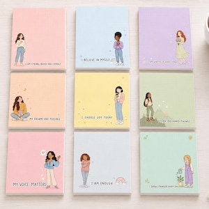 Op de afbeelding: Negen vierkante memoblokjes in pastelkleuren, elk met een unieke illustratie van een persoon en een motiverende tekst. De teksten zijn I AM STRONG, BRAVE AND SMART, I BELIEVE IN MYSELF, I AM WORTHY OF GOOD THINGS, MY DREAMS ARE POSSIBLE, I CHOOSE JOY TODAY, I CAN DO HARD THINGS, MY VOICE MATTERS, I AM ENOUGH en I GROW STRONGER EVERY DAY.