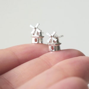 May include: A pair of silver earrings shaped like windmills. The earrings are small and delicate, and they would make a great gift for someone who loves windmills.