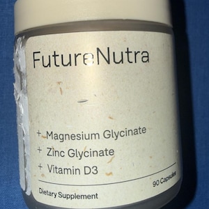 May include: A cylindrical dietary supplement bottle with a cream-colored lid and label. The label reads "Future Nutra" and lists ingredients: Magnesium Glycinate, Zinc Glycinate, and Vitamin D3. The bottle contains 90 capsules.