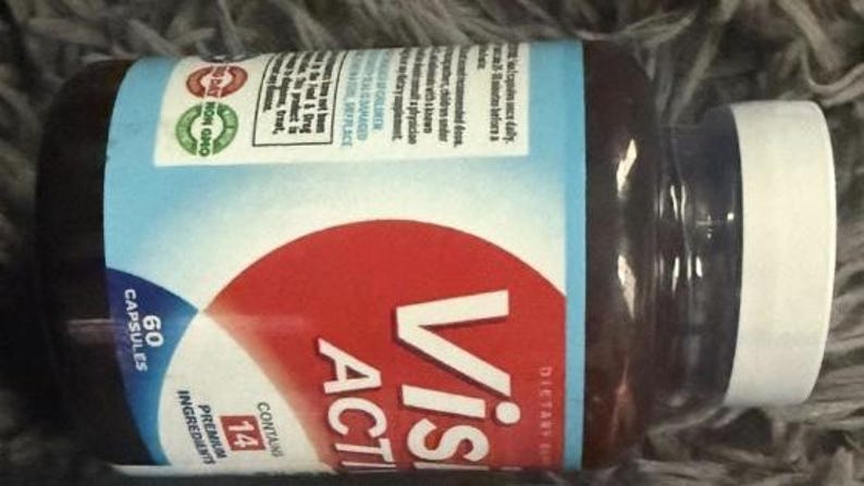 May include: A brown supplement bottle with a white lid. The label features the words "Visi Active" in white letters on a red background. The bottle contains 60 capsules and 14 premium ingredients.