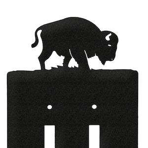 May include: Black metal light switch cover with a buffalo silhouette on top. The cover has two toggle switches.