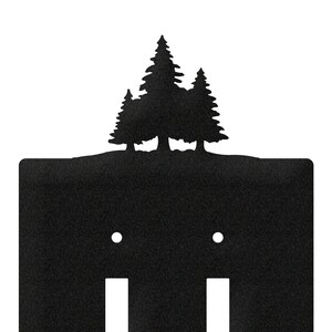 May include: Black metal double light switch cover featuring a silhouette of pine trees along the top edge. The cover has two toggle switch openings and two screw holes. A rustic, nature-inspired home decor accent.