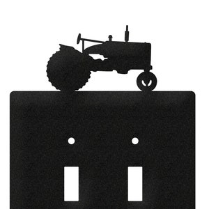 May include: Black metal light switch cover with a silhouette of a tractor on top. The switch cover has two toggle switches.