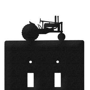 May include: Black metal light switch cover with a silhouette of a tractor on top. The switch cover has two toggle switches.