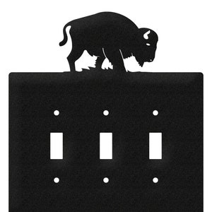 May include: Black metal light switch cover with a buffalo silhouette on top. The cover has three toggle switches.