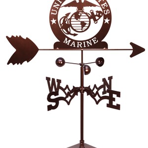 K&ouml;nnte beinhalten: Ein brauner Wetterhahn aus Metall mit einem Logo des United States Marine Corps, einer Windrose und einem Pfeil. Das Logo zeigt einen Globus, einen Adler und einen Anker. Die Windrose hat die Buchstaben N, S, E und W. Der Pfeil zeigt nach rechts.