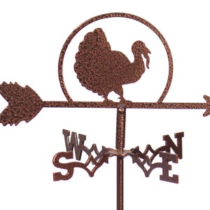 May include: A copper-colored metal turkey weather vane with a circular design around the turkey. The vane has an arrow pointing east and the letters N, S, E, and W on the base.