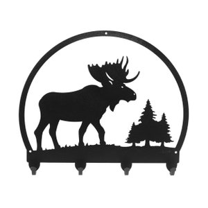 May include: Black metal moose silhouette key rack with five hooks. The moose is standing in a forest scene with two pine trees.