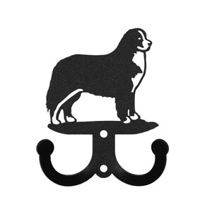 May include: Black metal double hook with a Bernese Mountain Dog silhouette on top. The hook is designed to hang coats, hats, or other items.