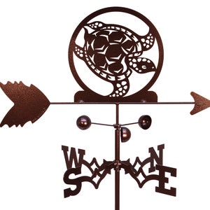May include: A brown metal sea turtle wind spinner with a compass rose and arrow. The turtle is in a circle with a cut-out design. The wind spinner is mounted on a pole.