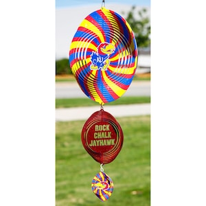 May include: A red, yellow, and blue spiral wind spinner with a Kansas Jayhawks logo. The spinner has a smaller red circle with the words "Rock Chalk Jayhawk" on it and a smaller blue and yellow spiral spinner.