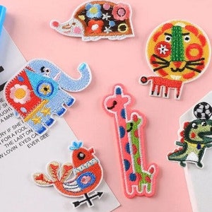 Könnte beinhalten: Eine Sammlung bunter, gestickter Aufnäher mit verschiedenen Tierdesigns. Enthält einen Igel, einen Löwen, einen Elefanten, eine Giraffe, einen Vogel und einen Dinosaurier. Die Aufnäher sind in Blau-, Rot-, Gelb-, Grün- und Rosatönen gehalten.