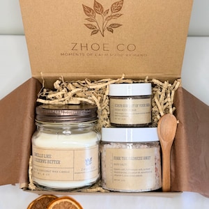 Könnte beinhalten: Geschenkbox mit Pflegeprodukten. Sie enthält eine Kerze, ein Zuckerscrub und Badesalze in Gläsern, einen HolzLöffel und getrocknete Orangenscheiben. Auf der Kerze steht "Smells Like Deserve Better". Die Box ist von der Marke "Zhoe Co".