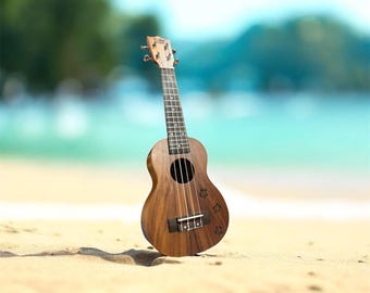 May include: A wooden ukulele on a sandy beach with a blurred ocean backdrop. The instrument features a circular sound hole and four strings. The ukulele is made of wood and has a natural finish. The beach is light tan, and the water is turquoise.
