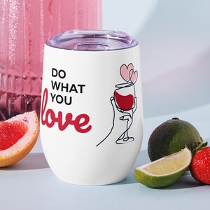Pode incluir: Um copo de vinho de aço inoxidável branco com um gráfico preto e vermelho que diz "Do what you love" e uma taça de vinho tinto com dois corações cor-de-rosa por cima.