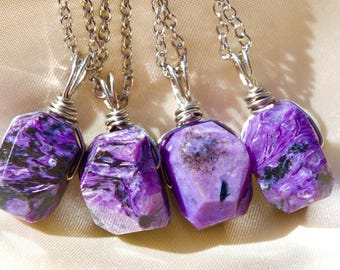 May include: Five silver chain necklaces with purple and black stone pendants. The stones are wrapped in silver wire.