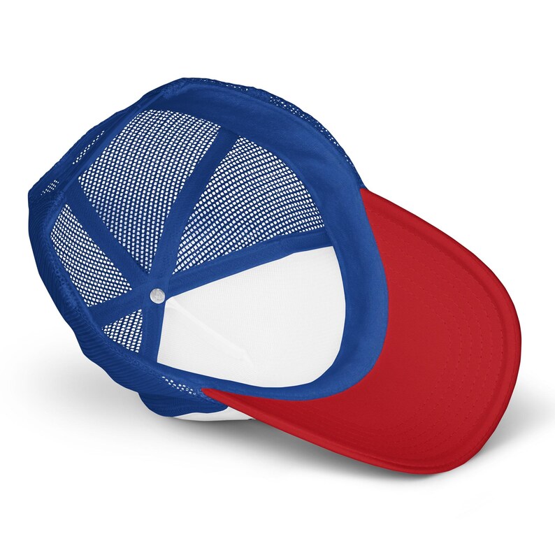 May include: A trucker hat featuring a bright red curved brim and a vibrant blue mesh back panel. The interior of the cap is lined with white fabric, showing the structural seams and the central button at the crown of the headwear piece.