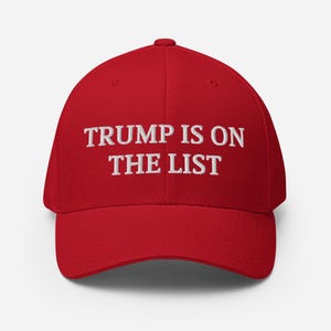 Könnte beinhalten: Rote Baseballkappe mit dem weißen, gestickten Text "TRUMP IS ON THE LIST". Die Kappe hat einen gebogenen Schirm und ein strukturiertes Design, geeignet für Freizeitkleidung.