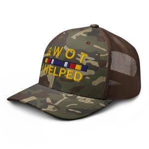 May include: Camouflage baseball cap with a brown mesh back. The front of the cap features the embroidered text "GWOT HELPED" in yellow, along with a colorful ribbon design. The cap has a curved brim.