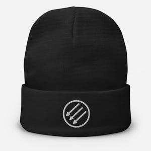 May include: Black beanie with a white embroidered design of three downward-pointing arrows inside a circle. The beanie has a folded cuff and a soft, knitted texture. This winter hat is a versatile accessory.