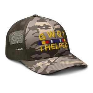 May include: Camouflage trucker hat with a mesh back and curved brim. The hat features the embroidered text "GWOT I HELPED" in yellow, with a colorful ribbon design above the text. The hat is a military-style accessory.