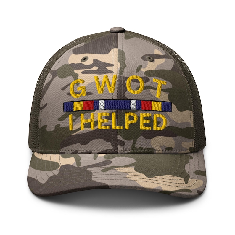 May include: Camouflage trucker hat with the text "GWOT HELPED" embroidered in yellow. The hat features a camouflage pattern on the front and a mesh back. A colorful ribbon design is above the word "HELPED".