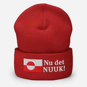 May include: A red beanie with a white and red Greenlandic flag patch and the text "Nu det NUUK!" in white. The beanie is made of a soft material and is designed to keep the head warm.