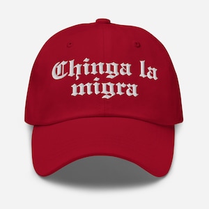 Può includere: Un cappellino da baseball rosso con la scritta ricamata "Chinga la migra" in bianco. Il cappellino ha una visiera curva e un cinturino regolabile sul retro.