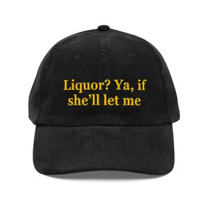 May include: Black corduroy baseball cap with the embroidered text "Liquor? Ya, if she'll let me" in yellow. The cap has a curved brim and a button on top. A casual accessory.