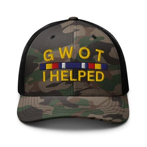 May include: Camouflage trucker hat with the embroidered text "GWOT I HELPED" in yellow. The hat features a black mesh back and a curved brim. The text is above a horizontal stripe design with red, white, and blue colors.