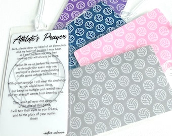 May include: A collection of rectangular luggage tags featuring a white tag with the black text Athlete's Prayer and a volleyball graphic, alongside other tags in purple, blue, pink, and gray, each patterned with a repeating white volleyball design.