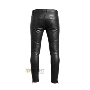 May include: Black leather trousers with ribbed knee panels and ankle zips. The trousers have a classic five-pocket design and a fitted silhouette. The back view of the trousers is shown against a white background.