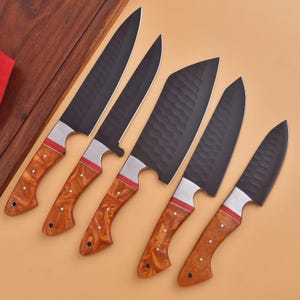 May include: A set of five kitchen knives with black, hammered-texture blades and brown, marbled-pattern handles. Each knife features a silver bolster with a thin red accent ring, three small rivets on the handle, and a hole at the end of the tang.
